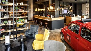 A modern interior with a bar area, seating, and a vintage car. - ibis Le Mans Centre Gare Nord (Le Mans)
