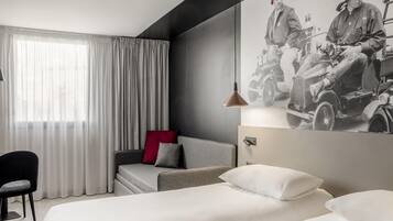 Ein modernes Hotelzimmer mit einem großen Bett, einer Couch, einem Sessel und einem Wandbild.