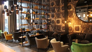 A cozy lounge area with a modern bookshelf, leather sofas, and a large mirror. - ibis Le Mans Centre Gare Nord (Le Mans)