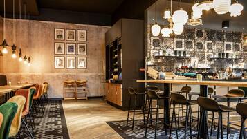 Un área de bar moderna con mostradores de madera, taburetes y lámparas colgantes.