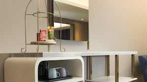 Eine kleine Küchenzeile mit Kühlschrank, Kaffeemaschine und einer Ablage für Snacks.
