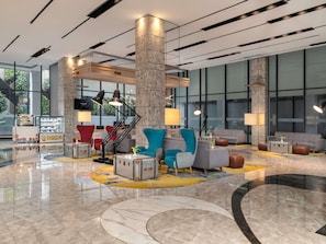A modern lobby with a central staircase, seating areas, and a polished marble floor.