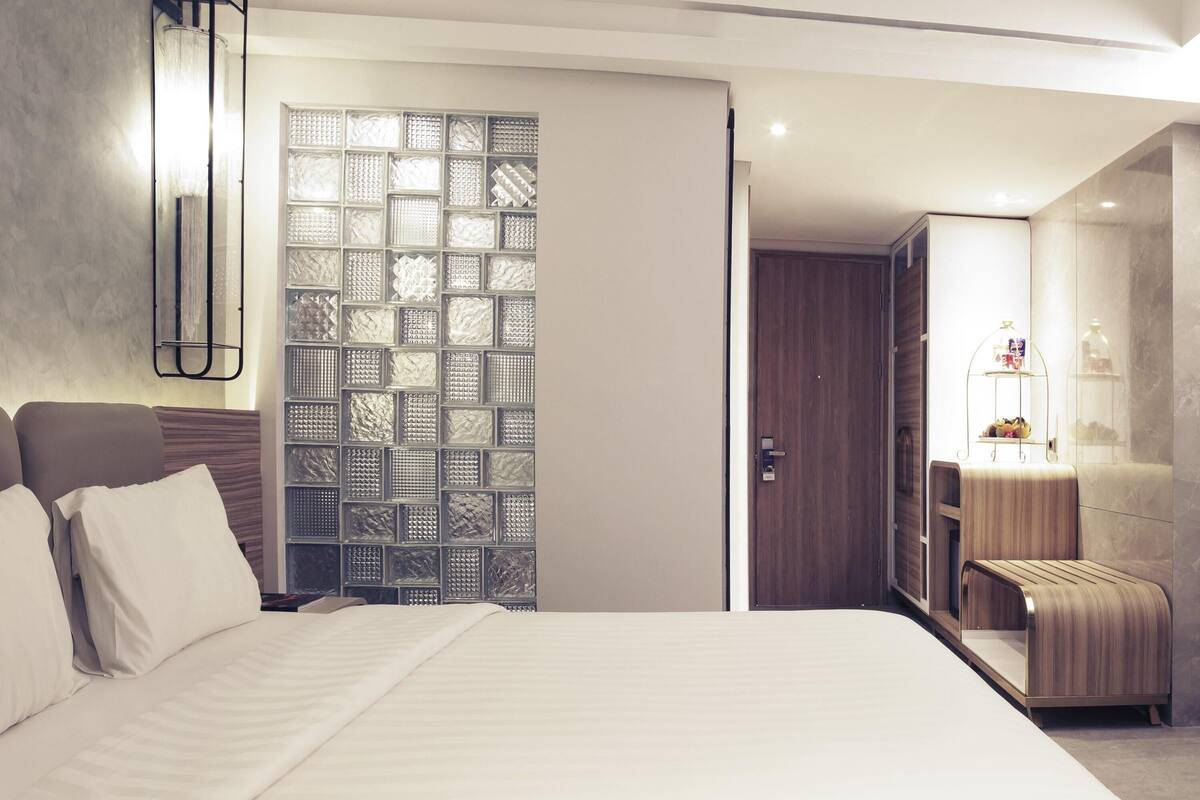 Ein modernes Hotelzimmer mit einem großen Bett, einem Kleiderschrank, einem Spiegel und einer dekorativen Wandverkleidung.