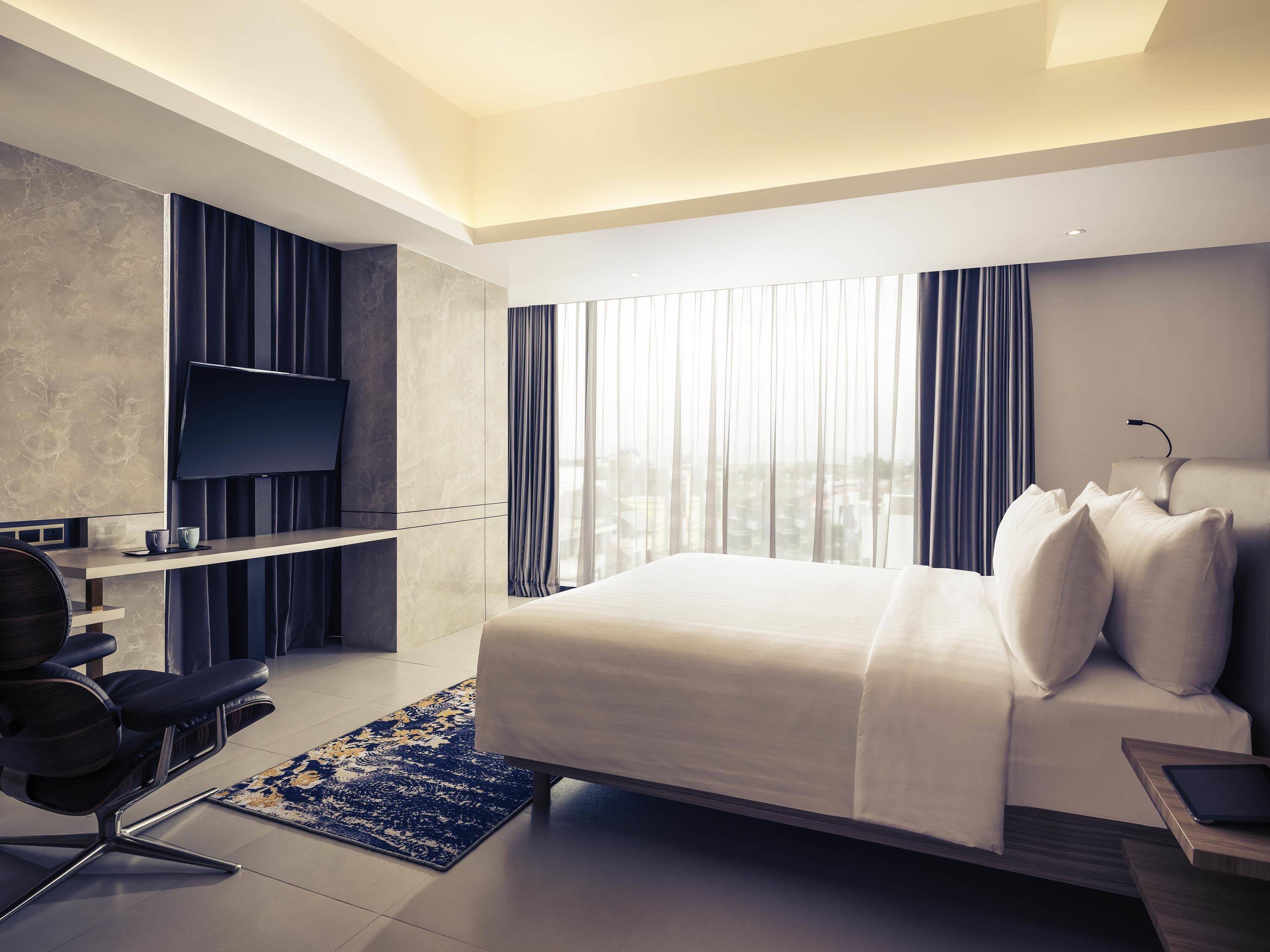 Une chambre d’hôtel moderne équipée d’un lit, d’un bureau, d’une chaise, d’une télévision et offrant une vue sur la ville.