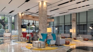 Eine moderne Lobby mit einer zentralen Treppe, Sitzbereichen und einem polierten Marmorboden.