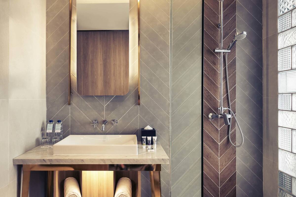 Ein Badezimmer mit Waschbecken, Spiegel, Handtuchhalter und Dusche.