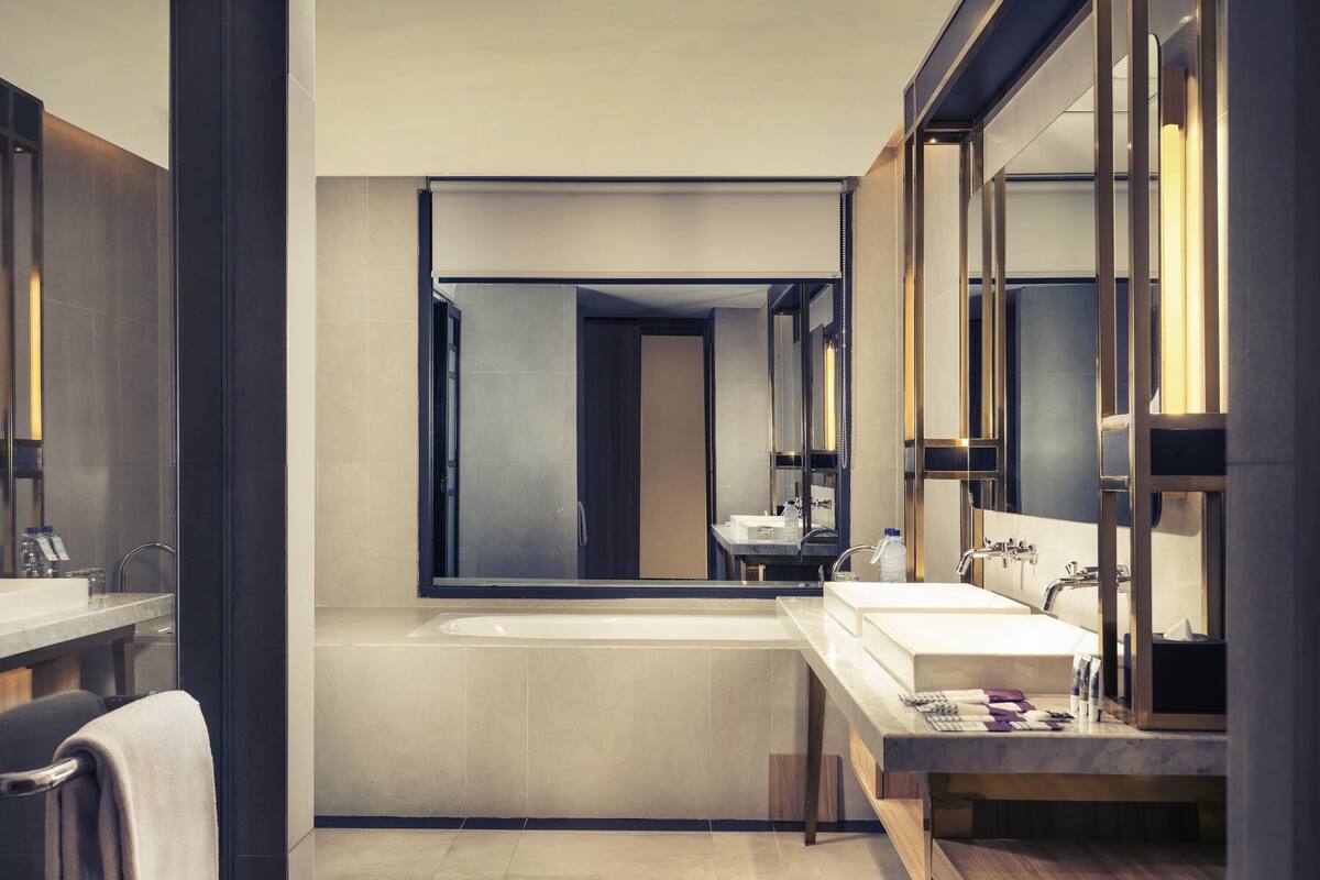Ein modernes Badezimmer mit einem großen Spiegel, einer Badewanne und einem Waschtisch.