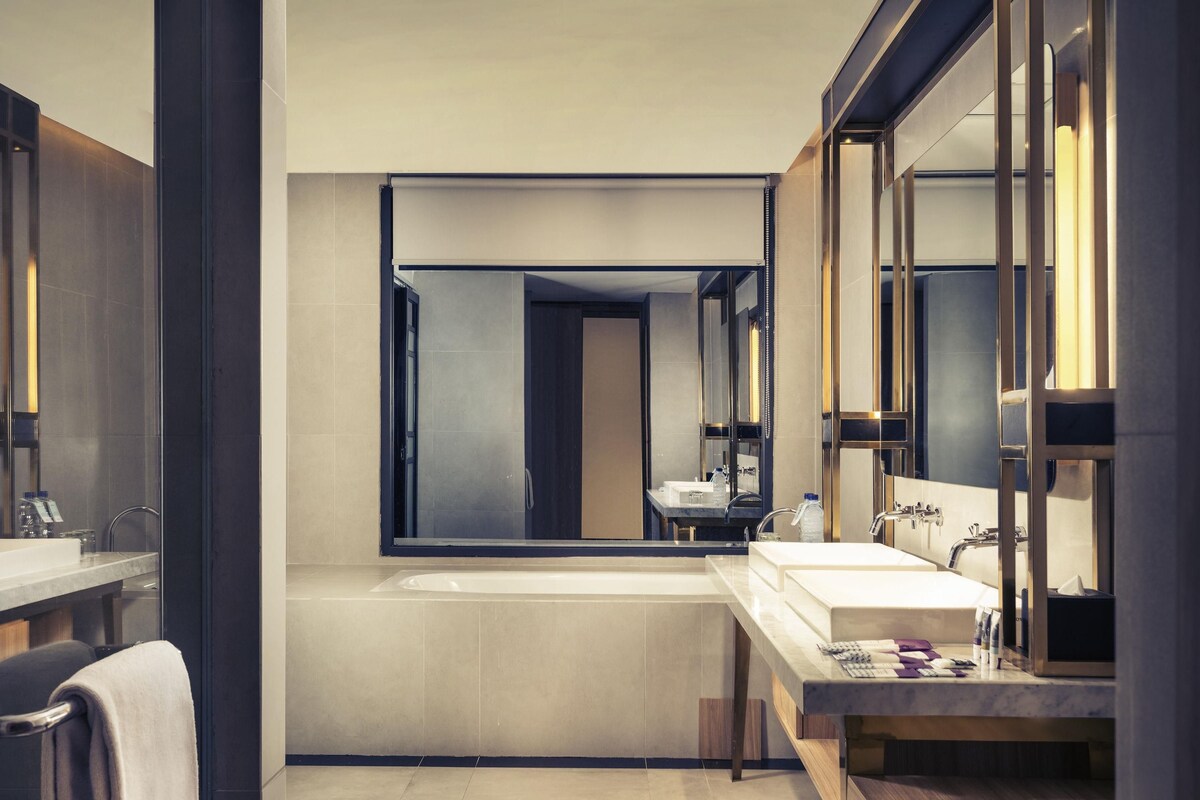 Une salle de bain moderne avec un grand miroir, une baignoire et un meuble-lavabo.