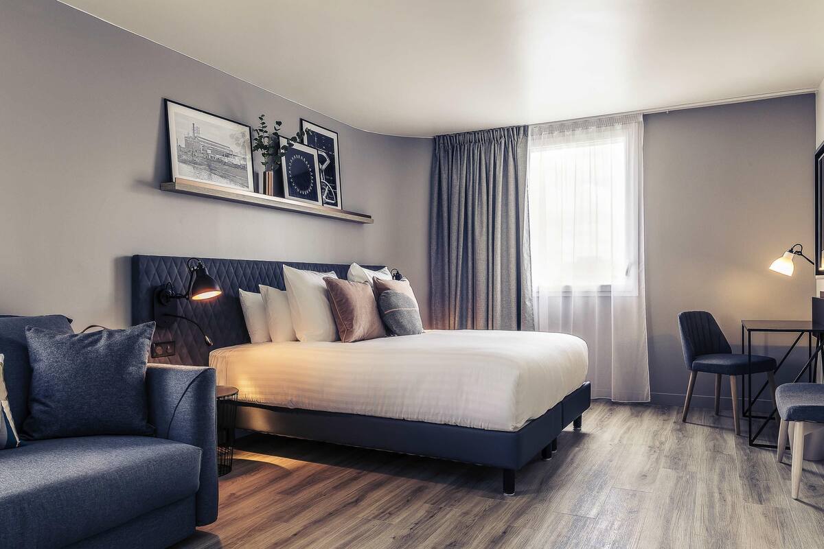Une chambre d’hôtel moderne équipée d’un lit, d’un canapé, d’un bureau et d’une chaise.