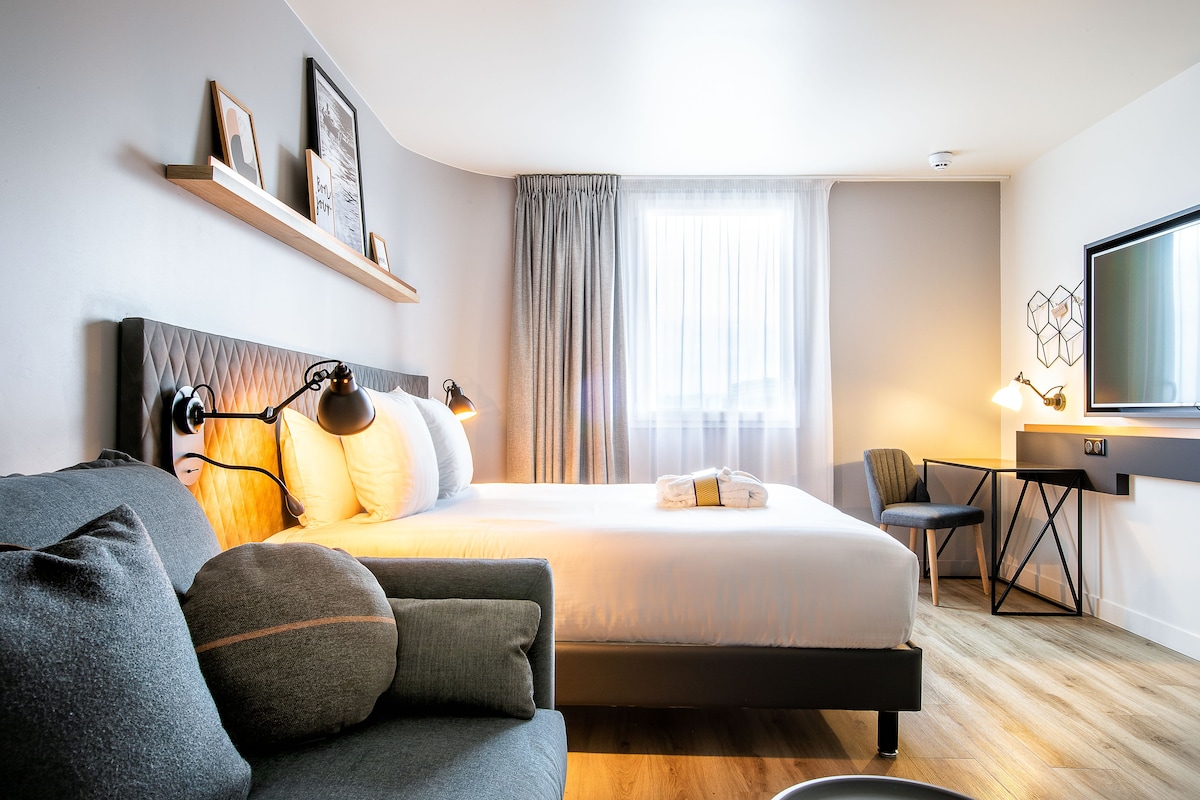 Une chambre d’hôtel moderne équipée d’un grand lit, d’un canapé, d’un bureau et d’une télévision.