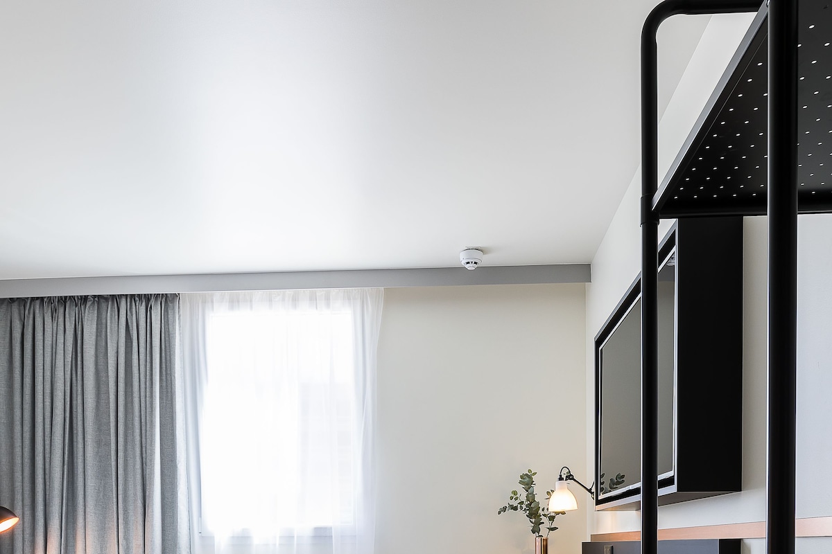 Une chambre d’hôtel moderne équipée d’un lit, d’un bureau, de chaises et d’un lit superposé.