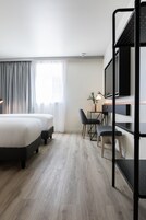 Una habitación de hotel moderna con cama, escritorio, sillas y literas.