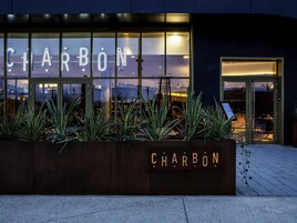 Un edificio con un gran letrero iluminado que dice 'CHARBON' y fachada de vidrio.