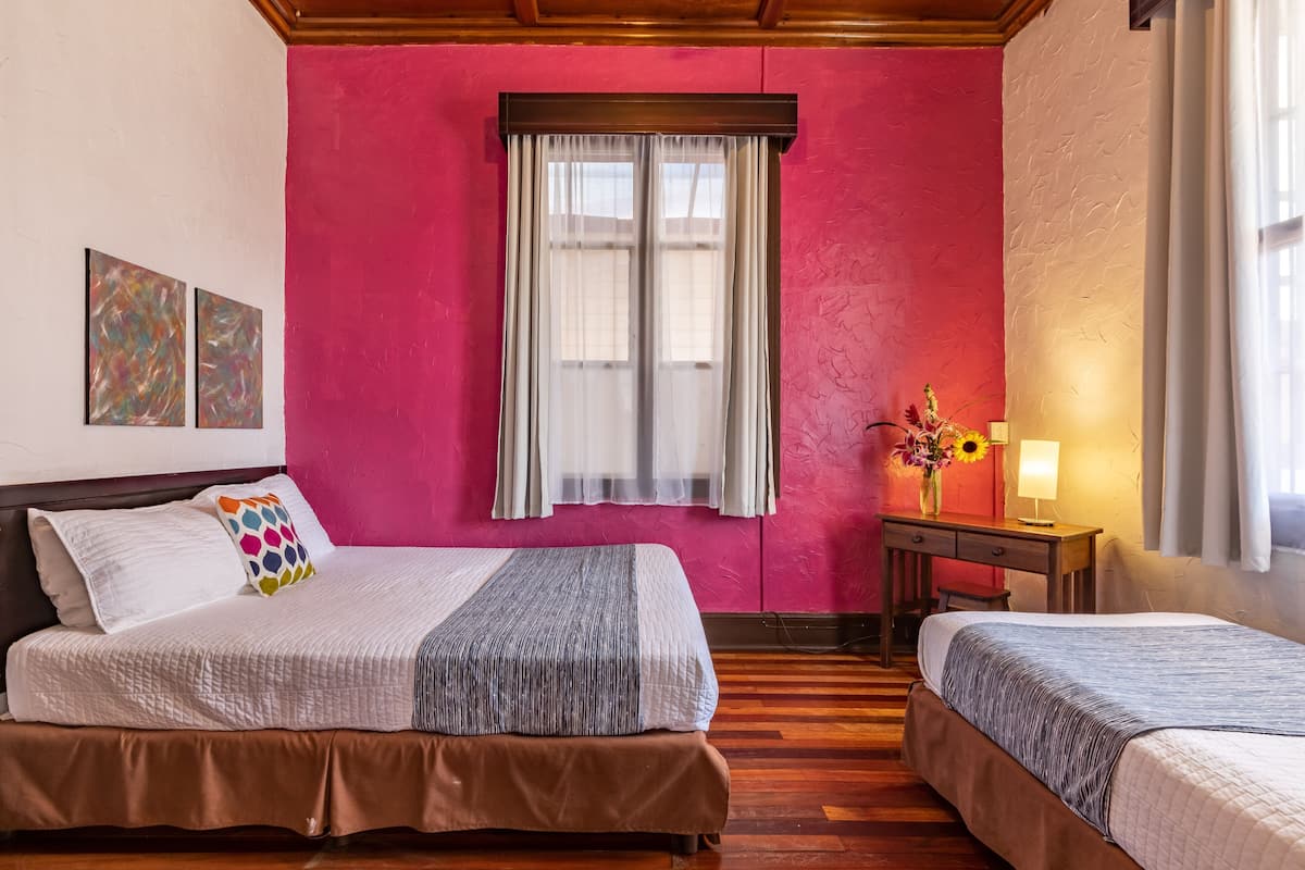 Una habitación con cama, escritorio y ventana con cortinas.