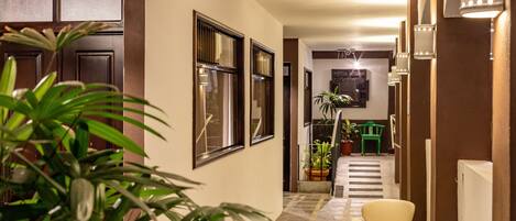 A hallway with a potted plant, a chair, and a table with items on it.