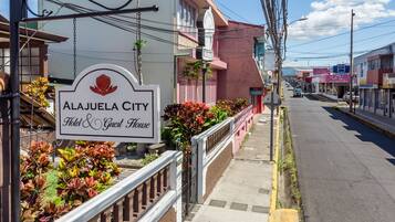 Un letrero de hotel con un logotipo de flor roja y el nombre 'Alajuela City Hotel & Guest House'.