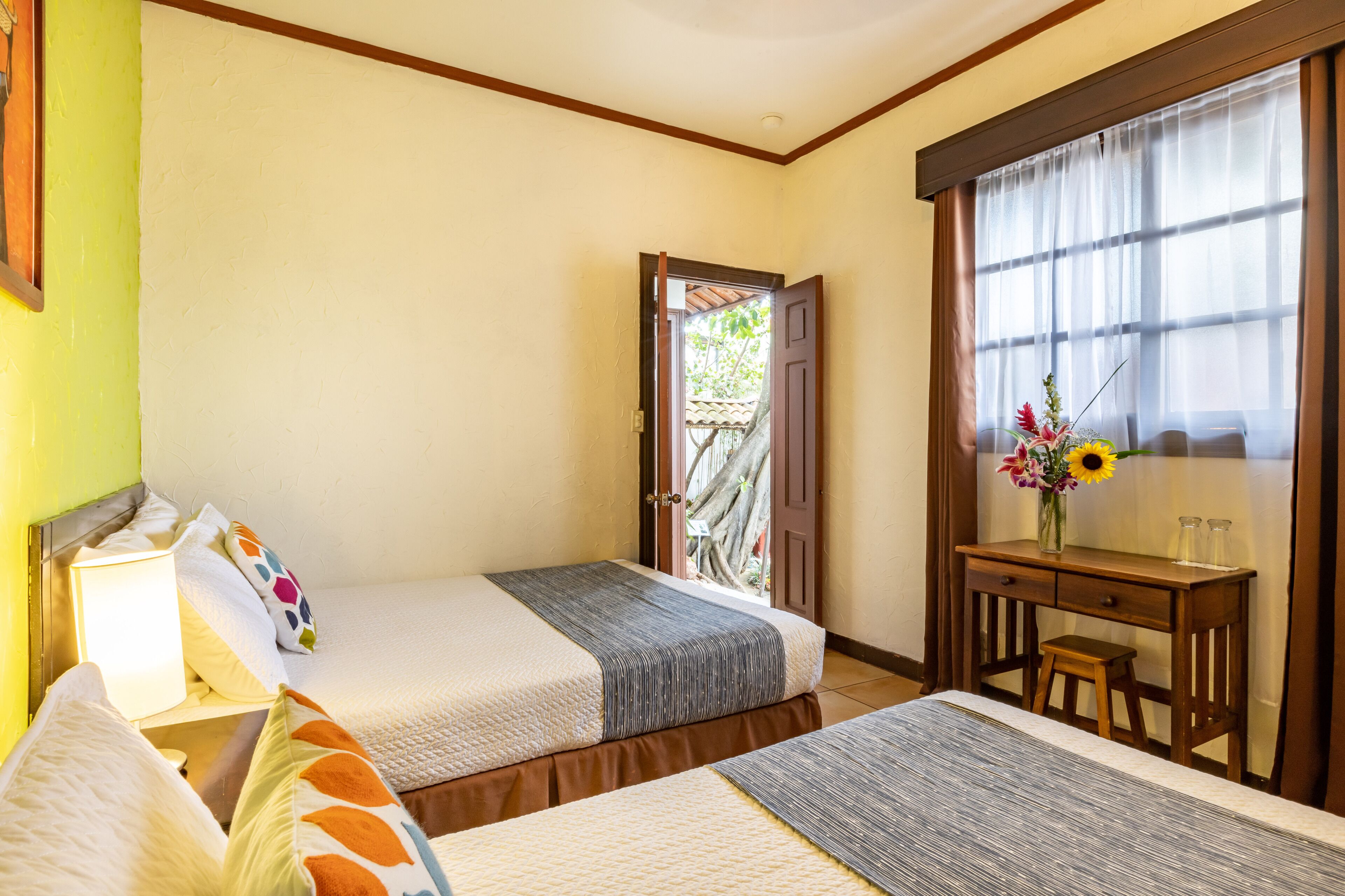 A hotel room with two beds, a desk, and a window with curtains.