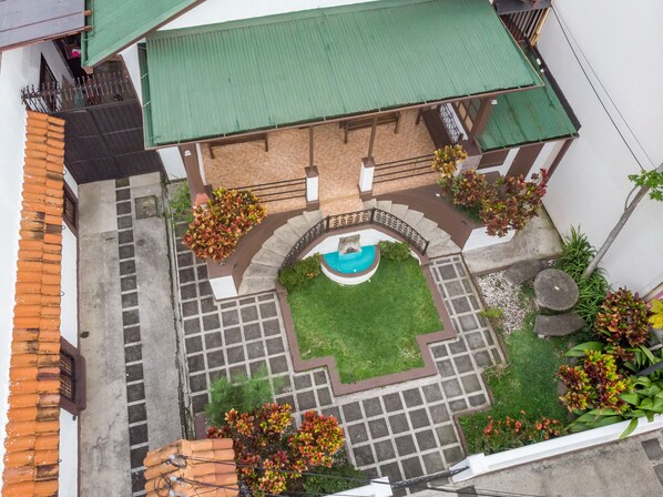 A courtyard with a swimming pool, surrounded by a stone pathway and greenery.