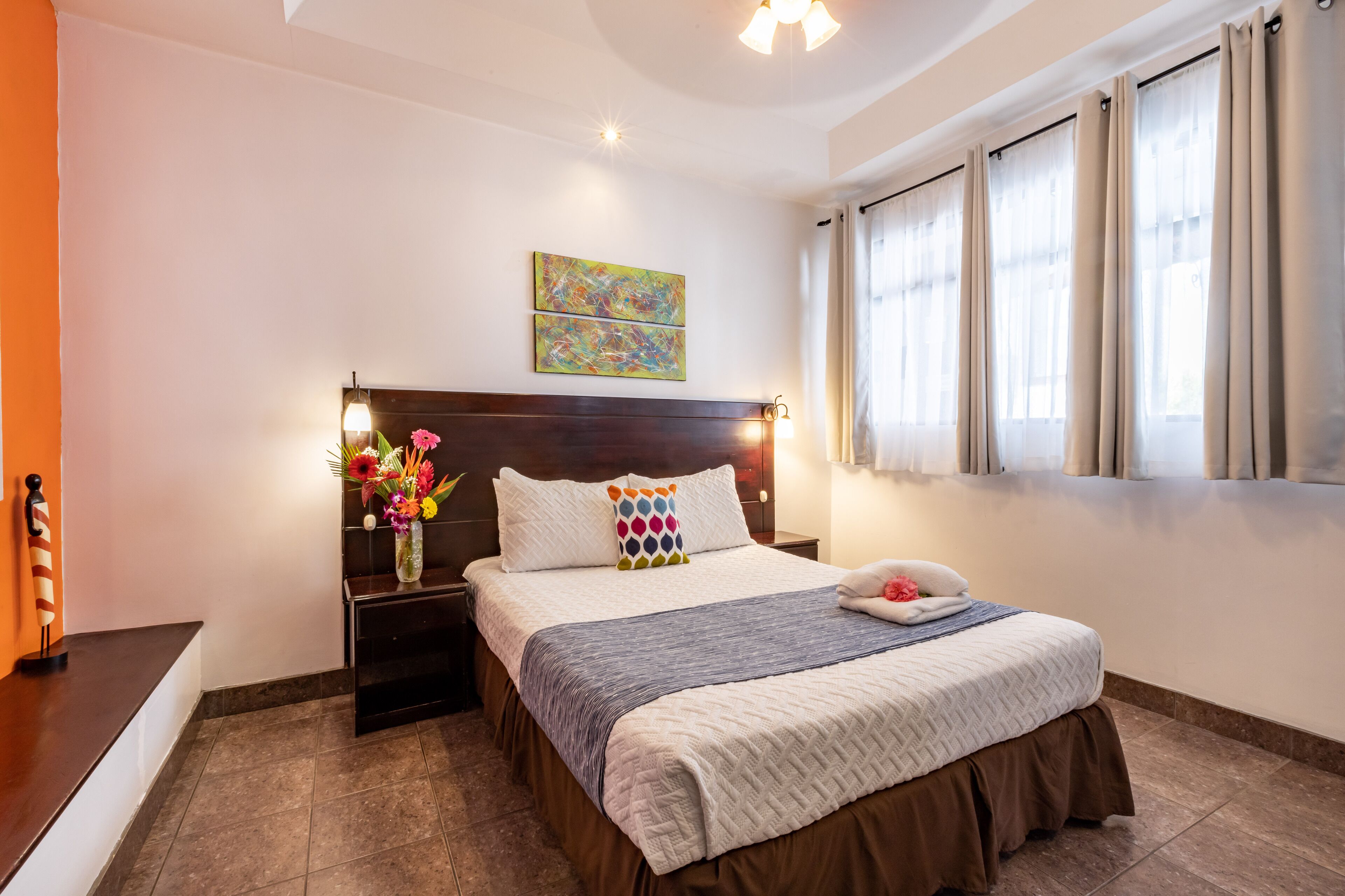 A neatly arranged bedroom with a bed, bedside tables, and a window with curtains.