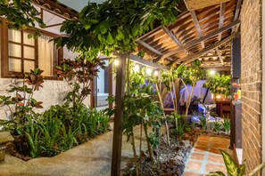 An outdoor garden area with a pergola, various plants, and a stone pathway. - Alajuela City Hotel & Guest House (Alajuela)