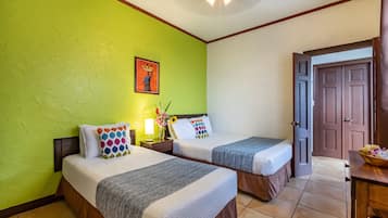 A hotel room with two beds, a green wall, a painting, and a wooden door.