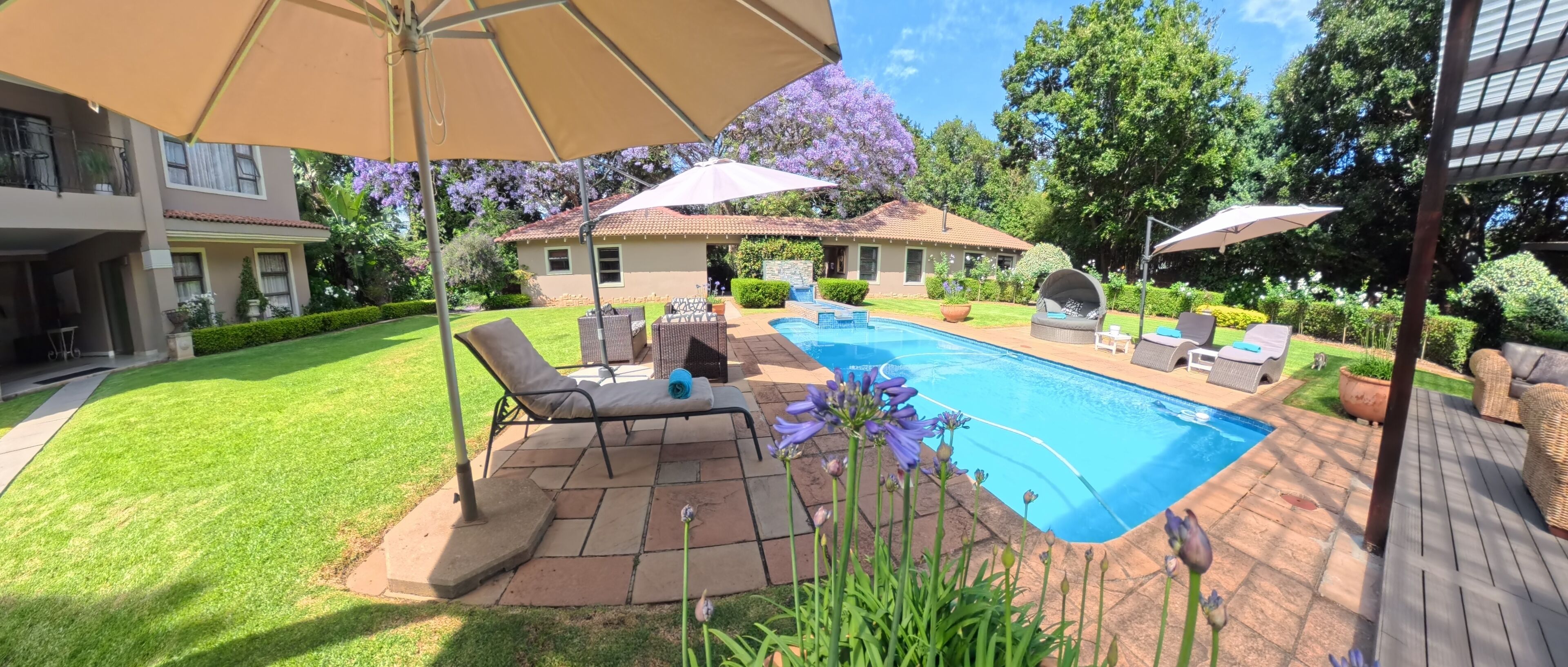 A backyard with a swimming pool, patio furniture, and a covered seating area.