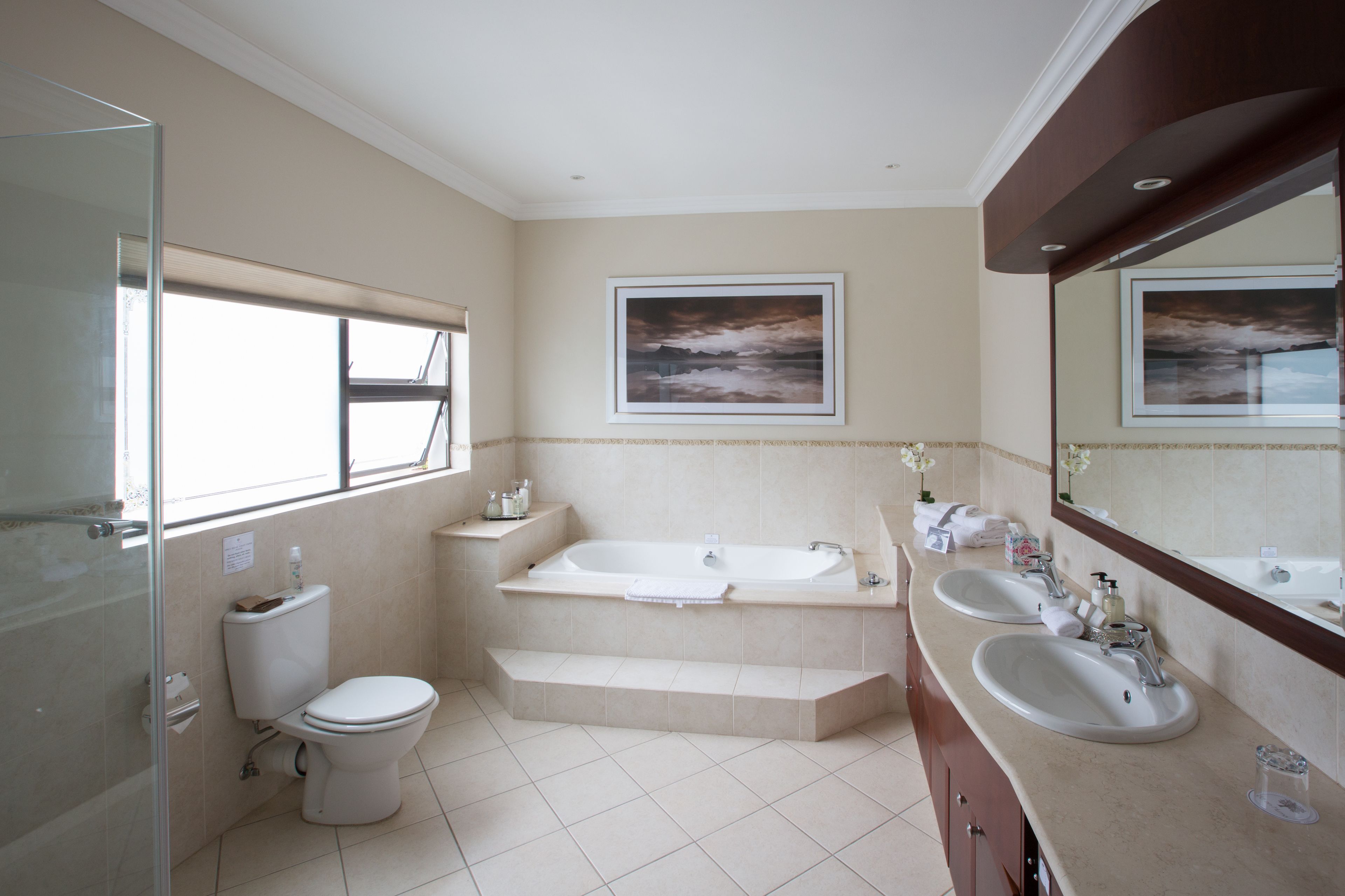 Un baño moderno con inodoro, bañera y dos lavamanos.