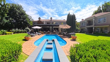 Un patio trasero con piscina, mobiliario exterior y un césped bien cuidado.
