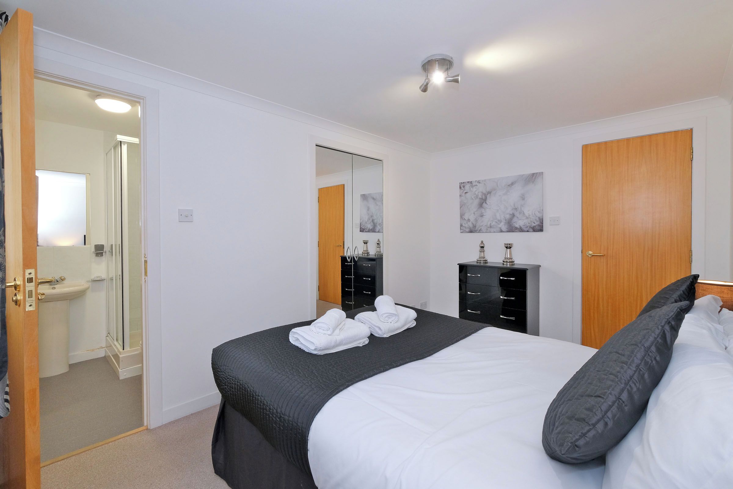 A hotel room with a bed, a bathroom, a wardrobe, and a mirror.