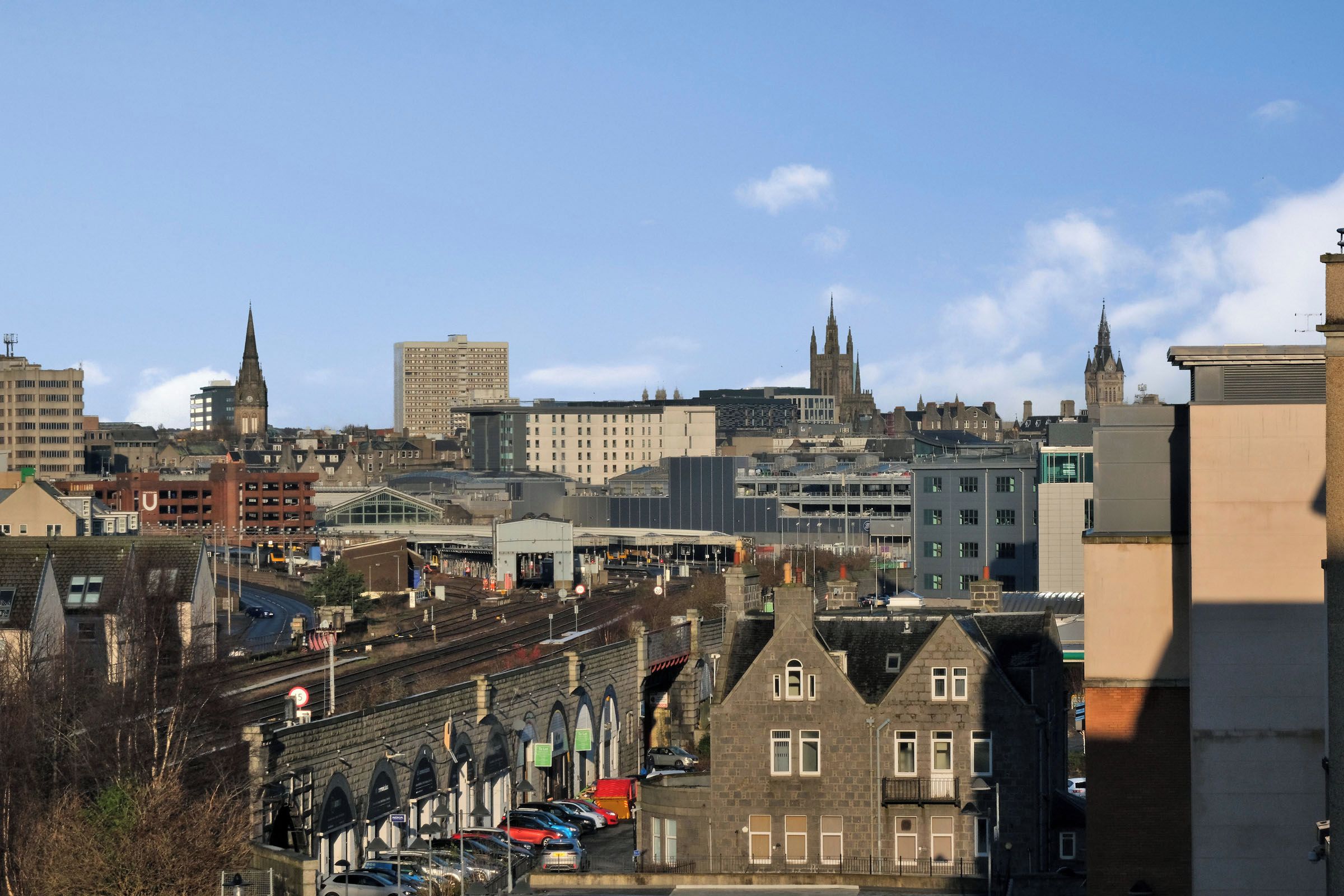 A cityscape with historic buildings, a modern train station, and a prominent cathedral.