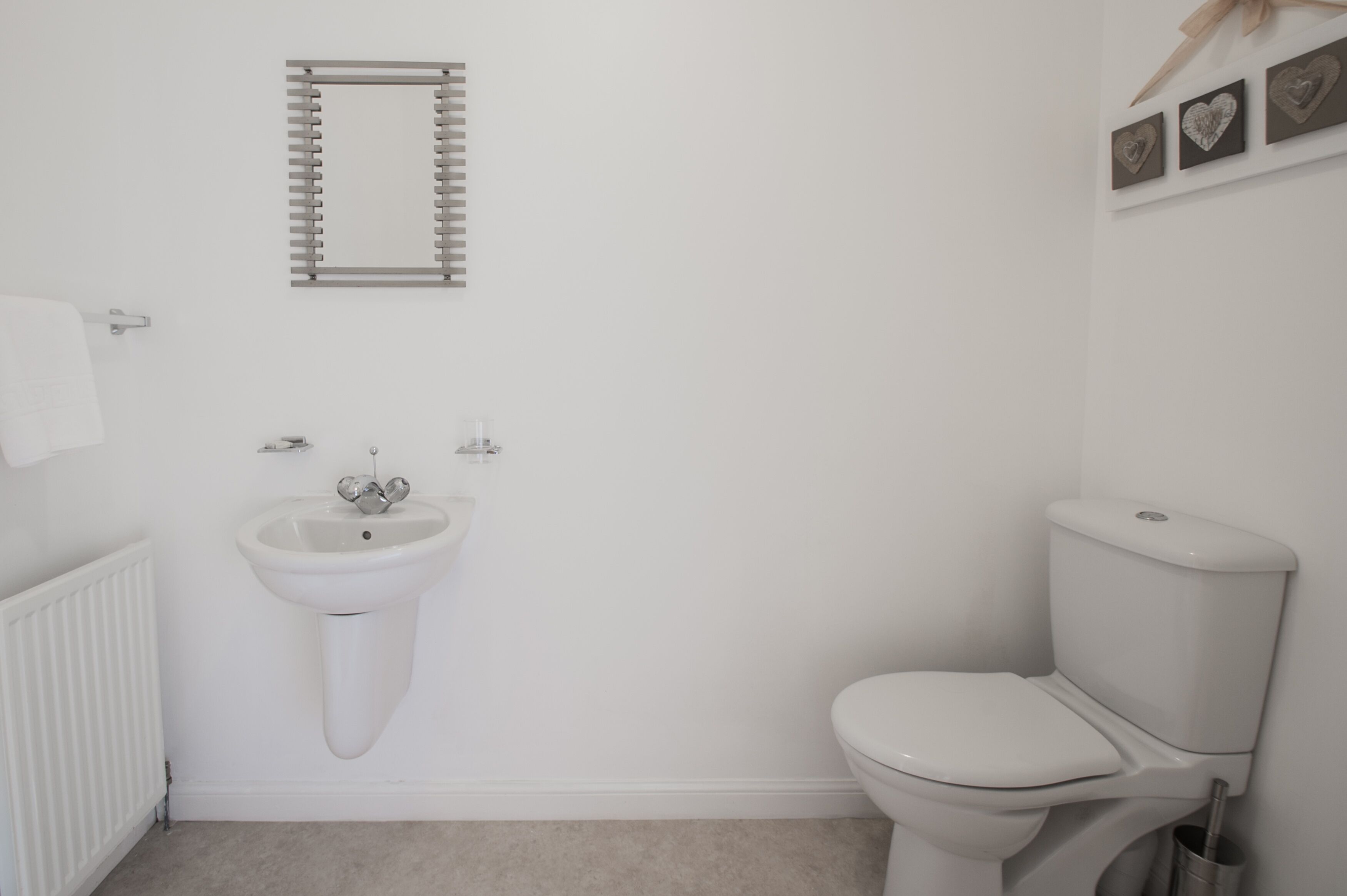 A bathroom with a white sink, toilet, and radiator.