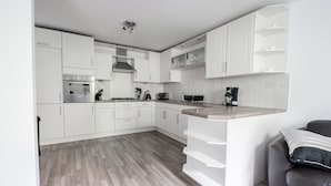 A modern kitchen with white cabinetry, a built-in oven, and a coffee machine. - Am Pm Cults Townhouses (Aberdeen)