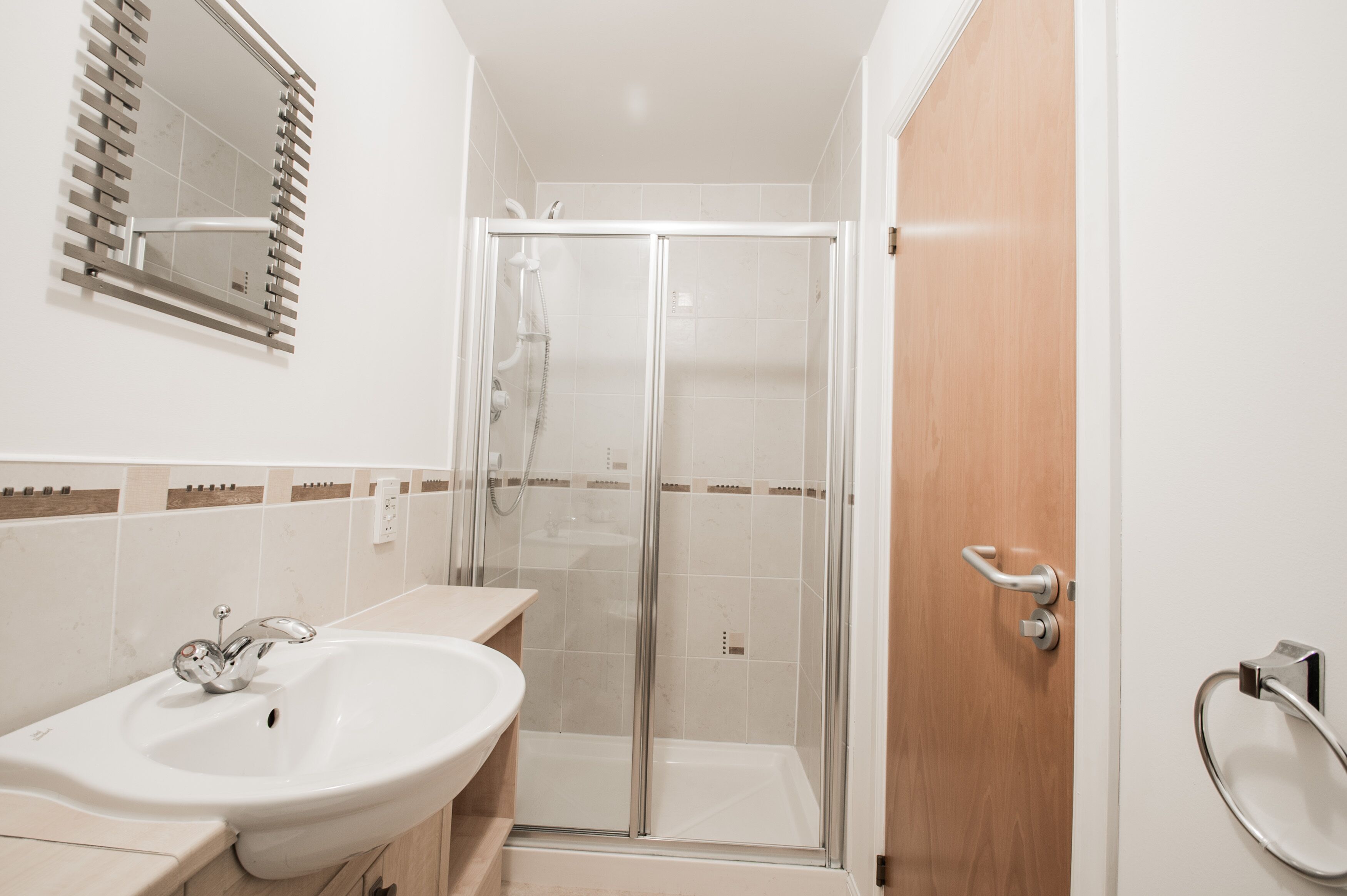 A bathroom with a shower, sink, and mirror.