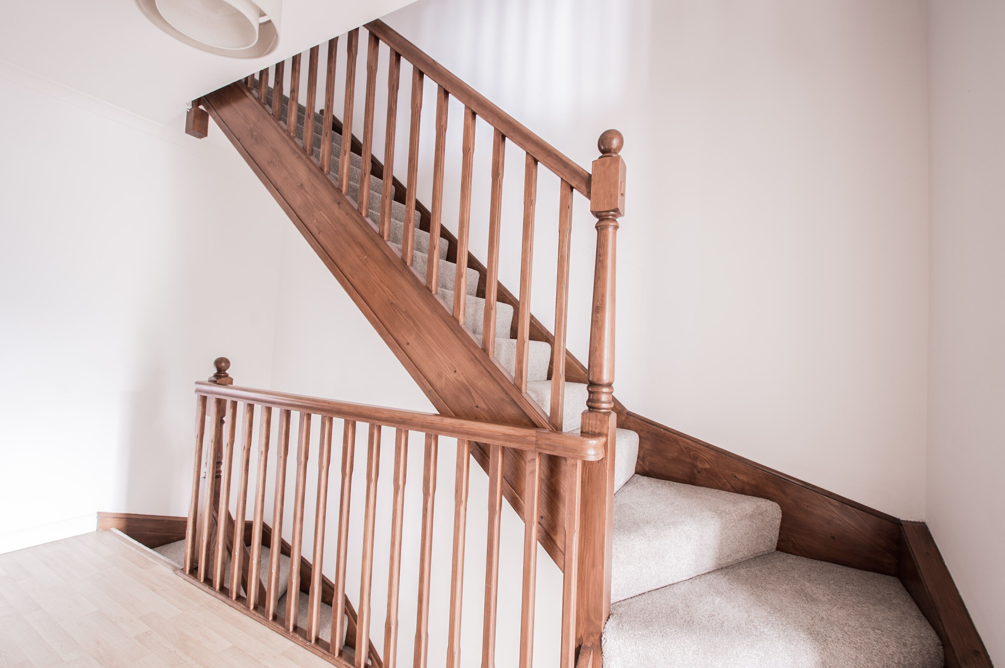 A wooden staircase with a handrail and carpeted steps.