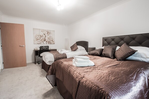 Un dormitorio ordenado con una cama grande, un escritorio y una silla.