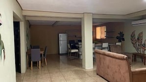 A spacious living area with a dining table and chairs, a sofa, and a refrigerator in the background. - Be My Guest Cabinas (Cahuita)