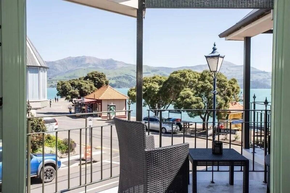 Ein Balkon mit Korbmöbeln, Blick auf einen Strand und ein Berg im Hintergrund.