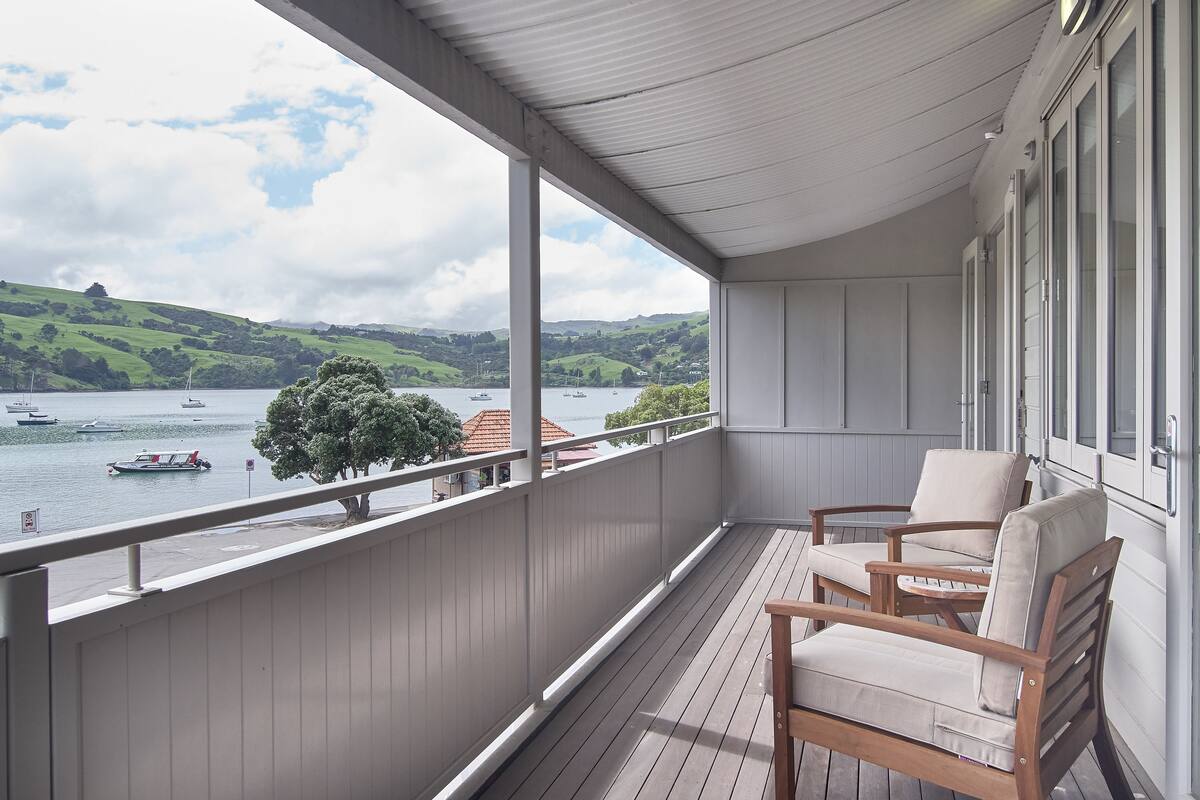 Ein Balkon mit Blick auf einen See, Boote und Hügel.