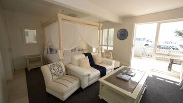 A bedroom with a four-poster bed, a sofa, a coffee table, and a view of the outside.