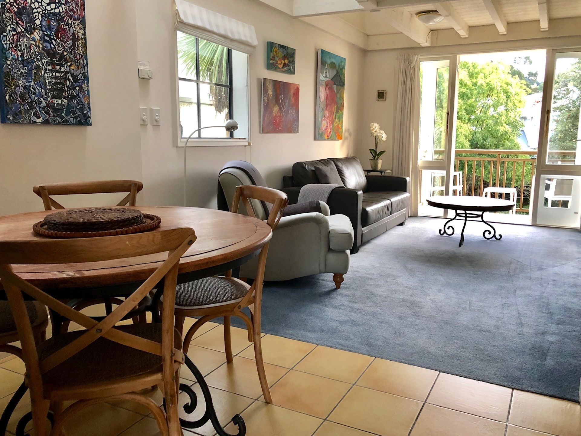 Una sala de estar con una mesa de comedor, sillas, un sofá y un balcón con vistas a zonas verdes.