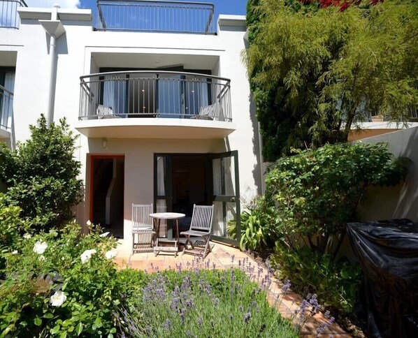 A two-story building with a balcony, outdoor seating area, and lush greenery. - Akaroa Village Inn (Akaroa)
