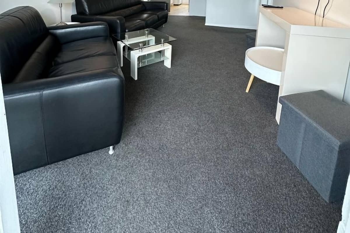 Ein modernes Wohnzimmer mit einem schwarzen Ledersofa, einem Glastisch und einem flachbildfernseher an der Wand.
