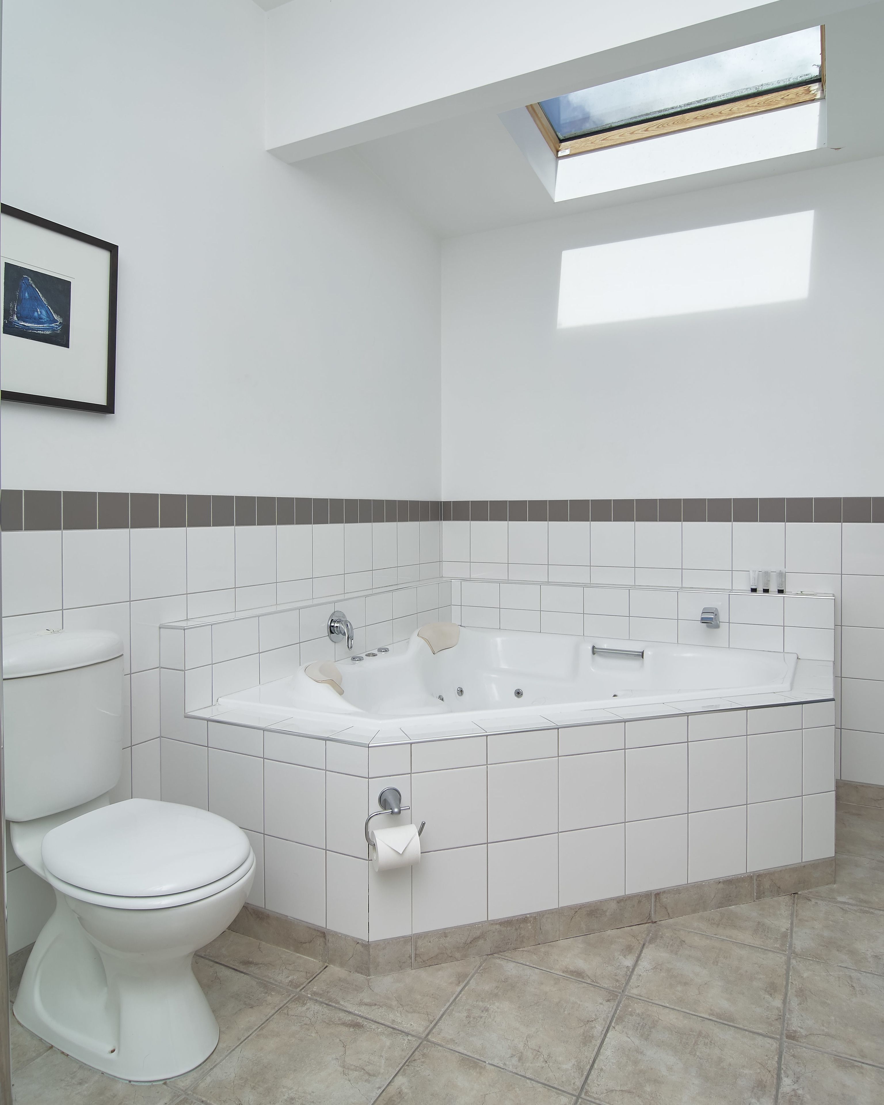 Une salle de bain moderne avec une baignoire blanche, des toilettes et un sol carrelé.