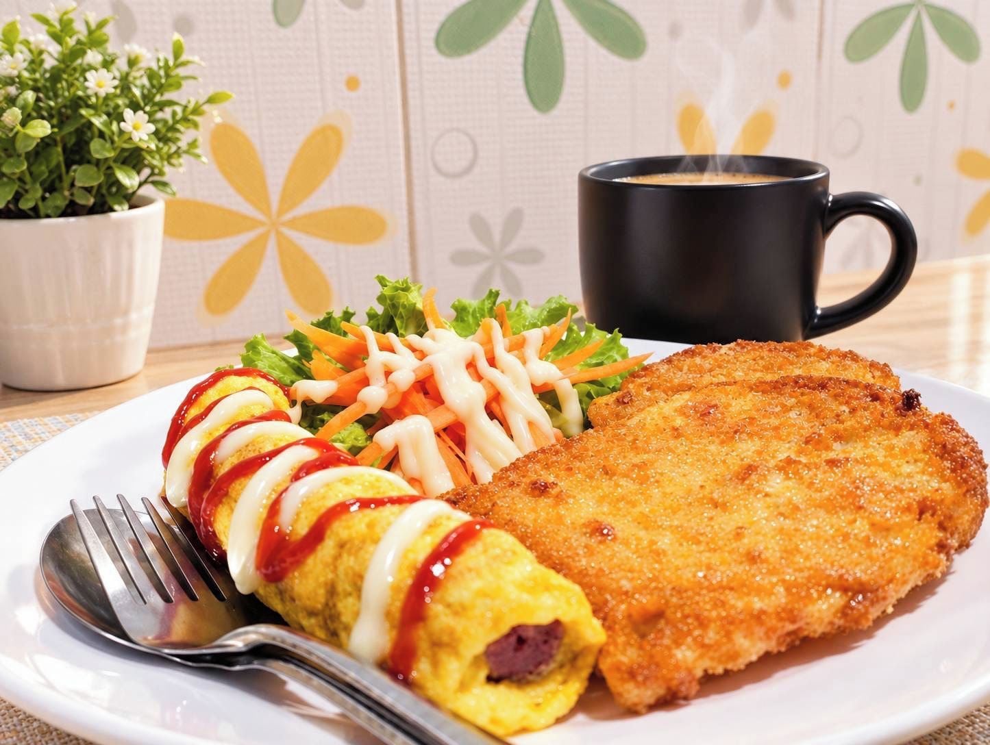 A plate with a breaded cutlet, a rolled omelette with sauce, and a salad with carrots and lettuce.