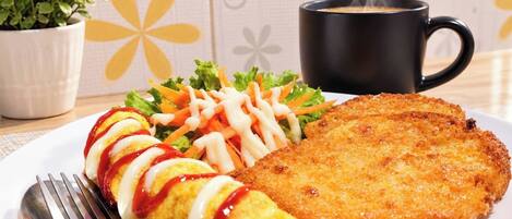 A plate with a breaded cutlet, a rolled omelette with sauce, and a salad with carrots and lettuce.