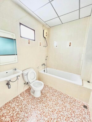 A bathroom with a toilet, sink, and bathtub. - Sirasit 999 Mansion (Phetchaburi)