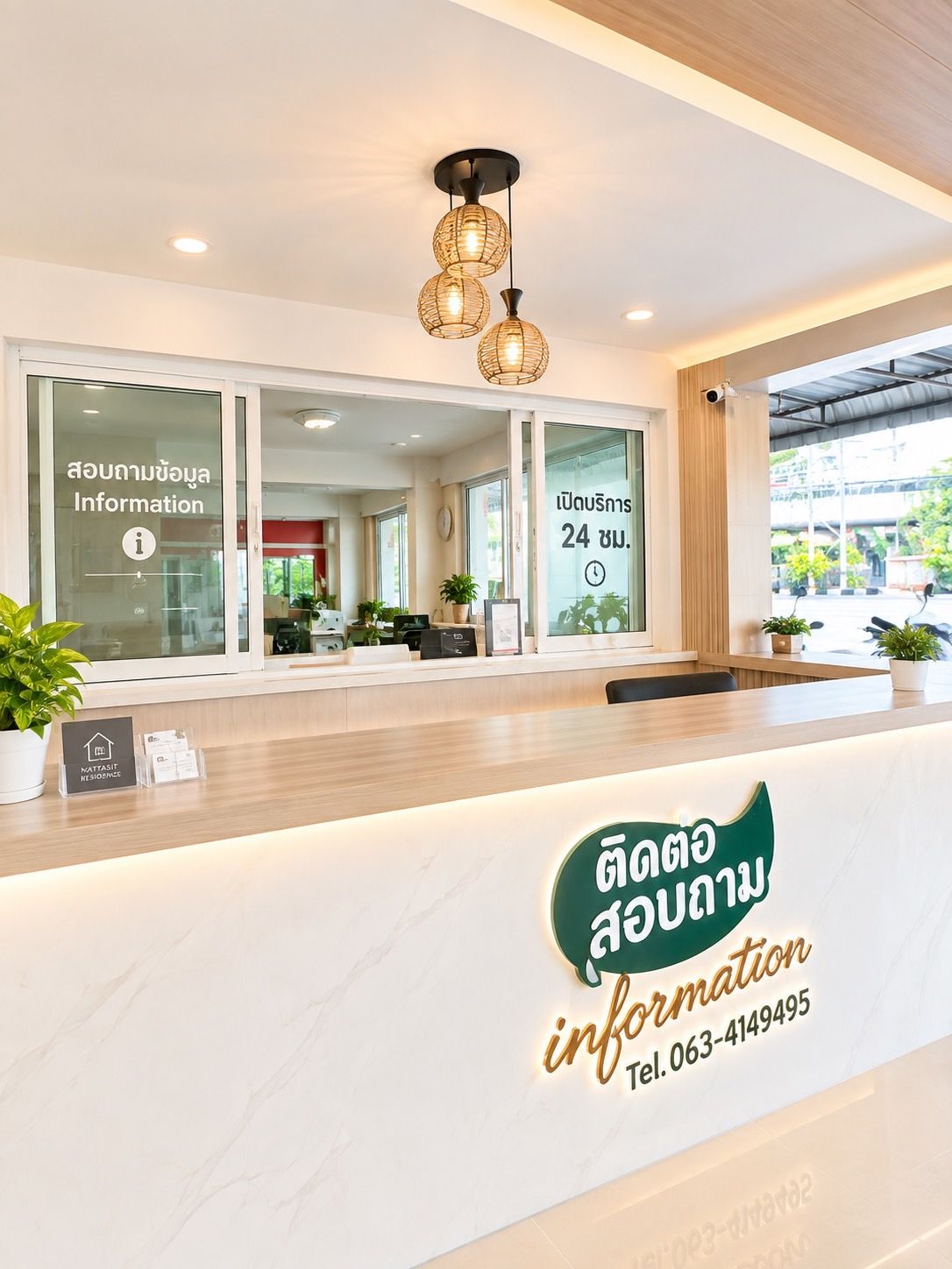 Un comptoir d’accueil avec une pancarte indiquant un service disponible 24 heures sur 24, un téléphone et une plante.