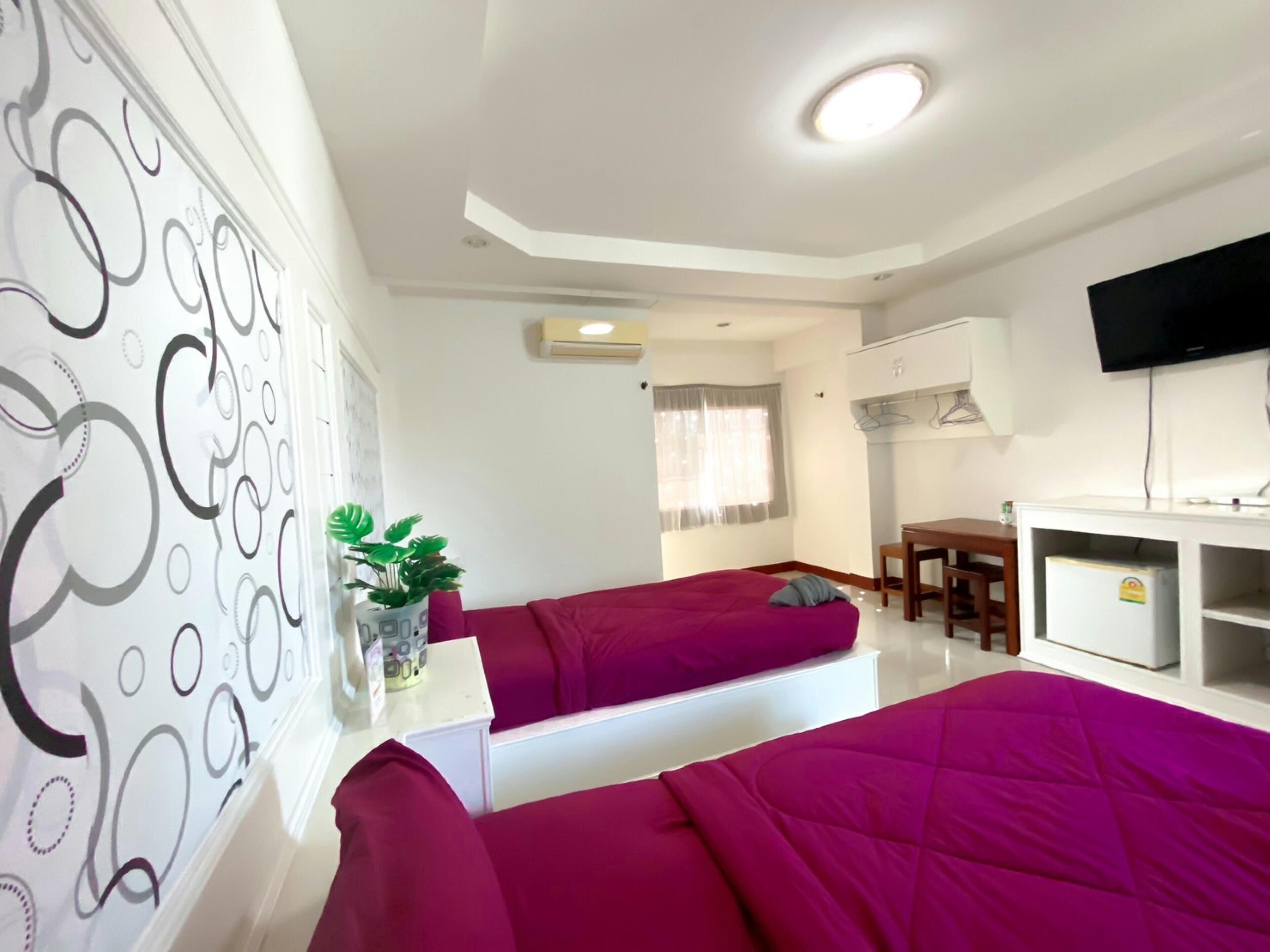 Habitación de hotel con dos camas, un escritorio, un televisor y una planta.