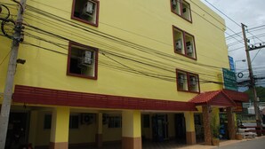 Um edifício amarelo de vários andares, com janelas emolduradas a vermelho e telhado vermelho.