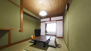 Une pièce de style japonais traditionnel, avec un sol recouvert de tatamis, une table basse, des coussins et des portes coulissantes.